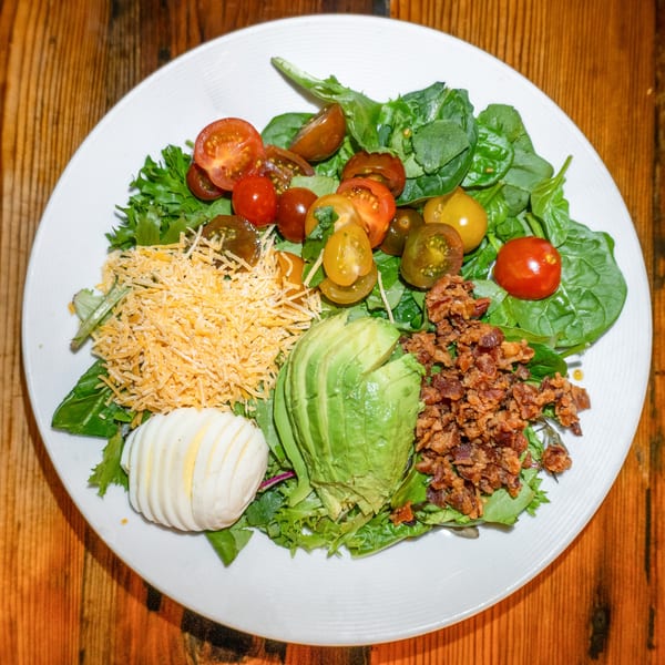 A Girl in the Park Cobb salad with greens, tomatoes, cheese, avocado, bacon, and egg.